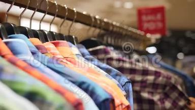 客户选择彩色<strong>男装</strong>衬衫在销售机架上。 年轻女子在服装<strong>店</strong>为男友寻找礼物。 4K.